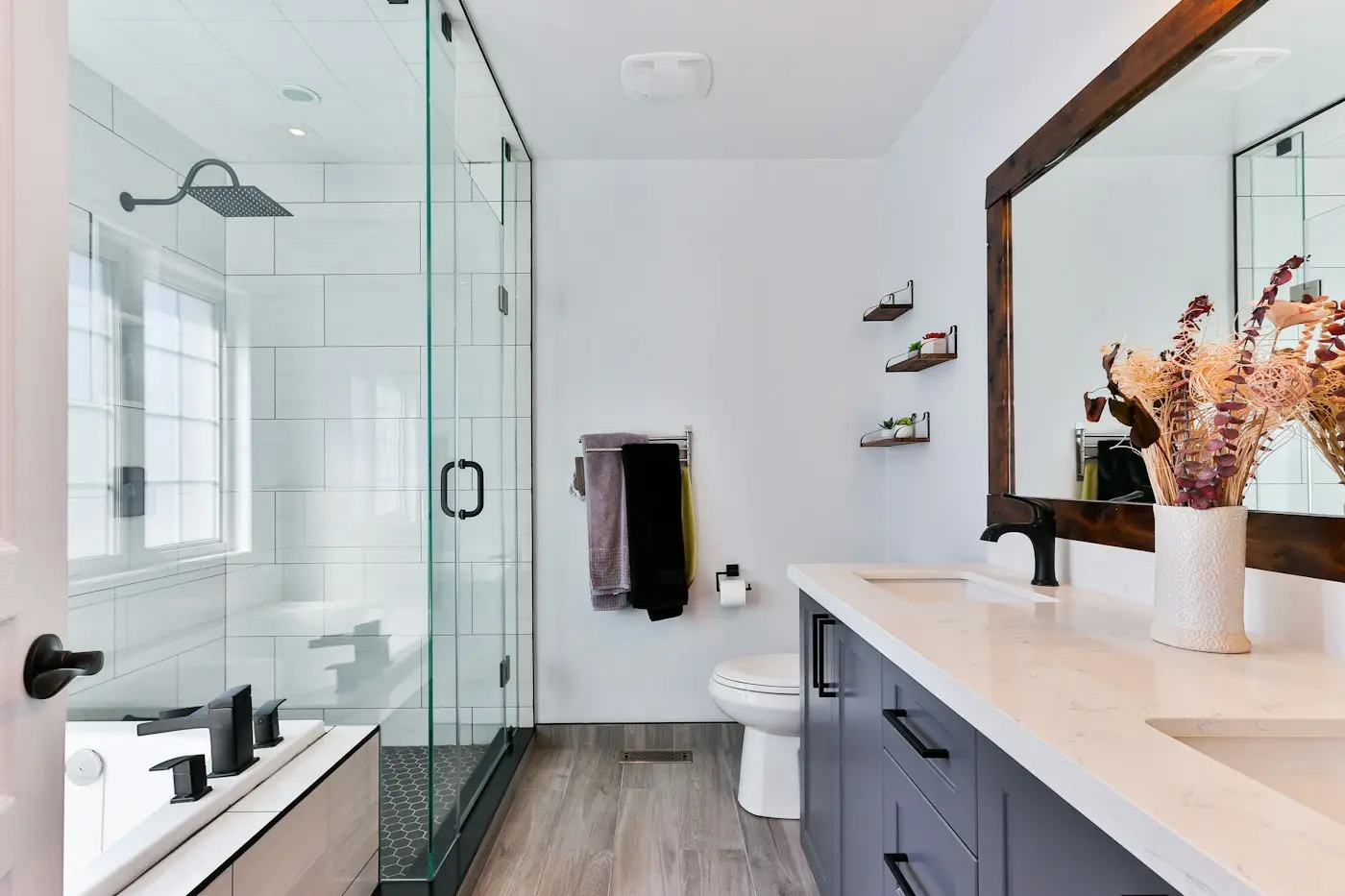 Baño con ducha cerrada por mampara de vidrio y mueble de lavabo