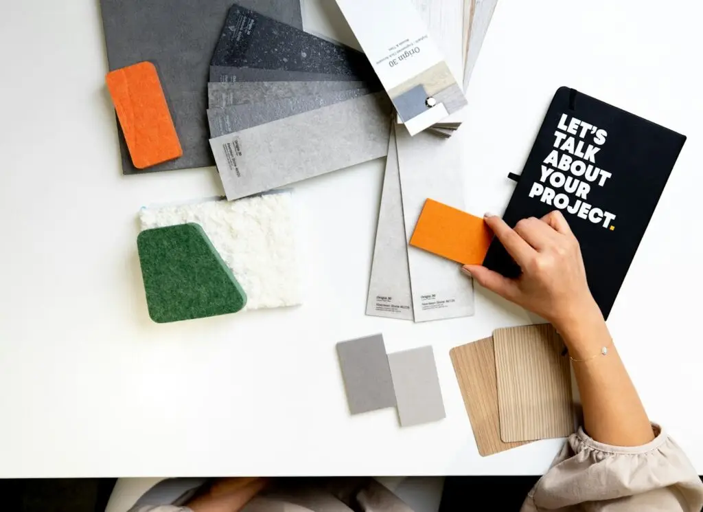 Manos comparando muestras de color y materiales sobre una mesa
