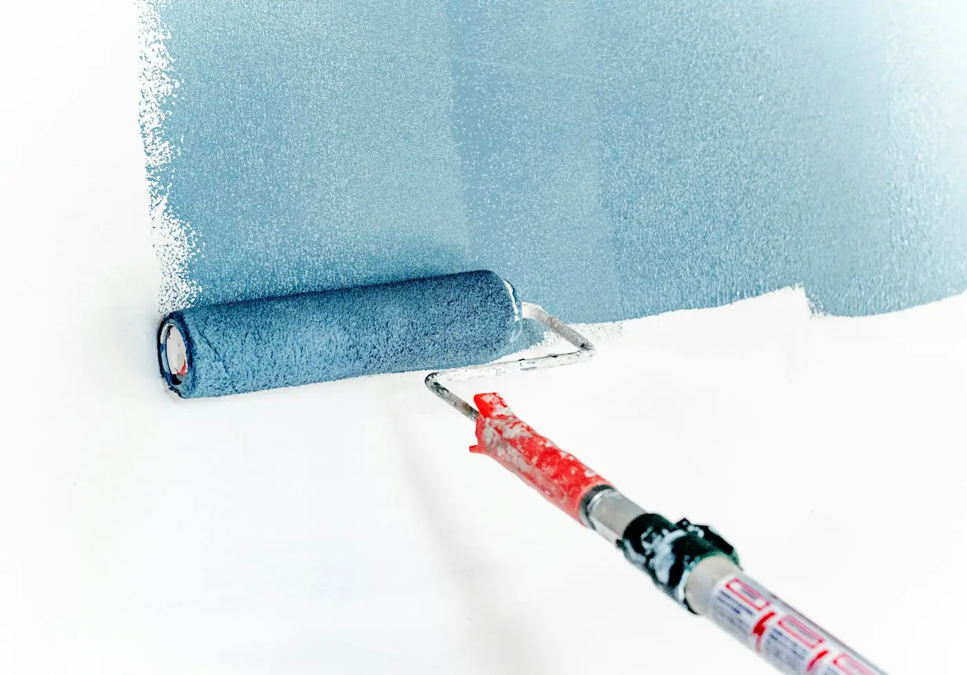 Rodillo aplicando pintura azul sobre una pared lisa